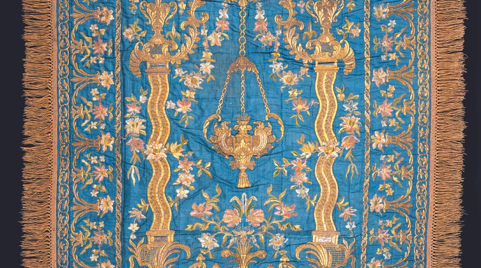 Blue silk altar cloth embroidered with gold columns, a hanging lamp, and flowers